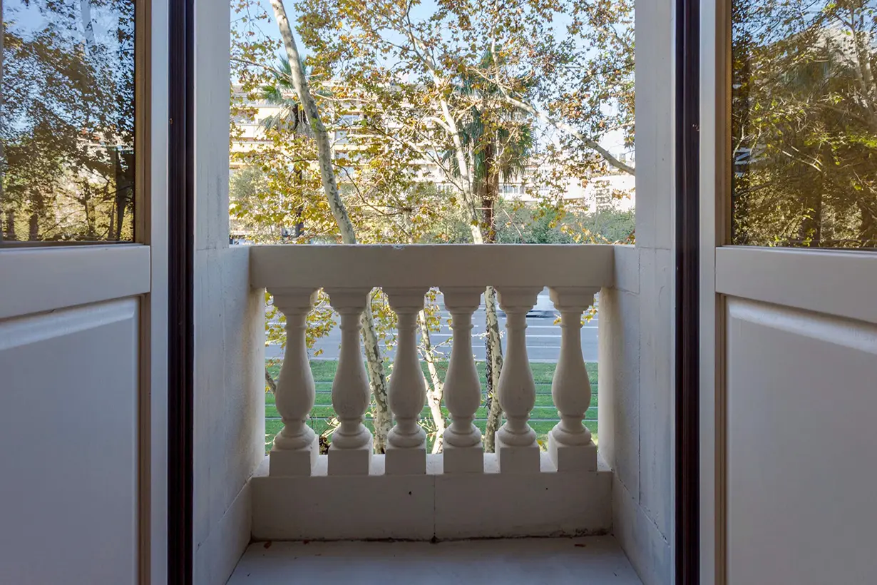 Balconera de madera a medida abierta a balcón con balaustrada de piedra en edificio histórico de Barcelona